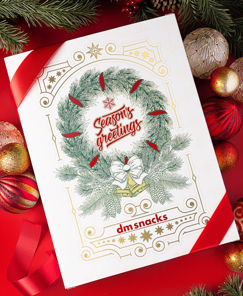 front view of The 24 Days of Nuts and Snacks surrounded by festive decorations.