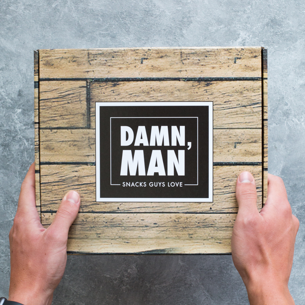 Hands holding Damn, Man gift box with gourmet snacks for men