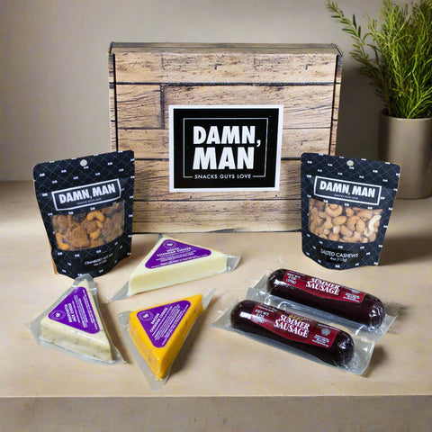Snack box with 'Damn, Man' branding on a wooden surface with snacks displayed.