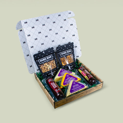 Gift box with snacks and cheeses on a light beige background